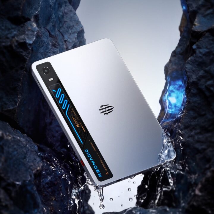 Silver smartphone with blue LED-side panel nestled between dark rocks with splashing water around it, showcasing a rugged/techy design.