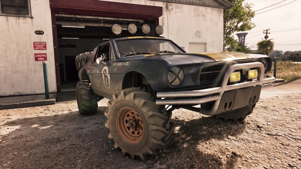 Lifted Vintage Muscle Car with Oversized Off road Tires Parked Outside a Workshop