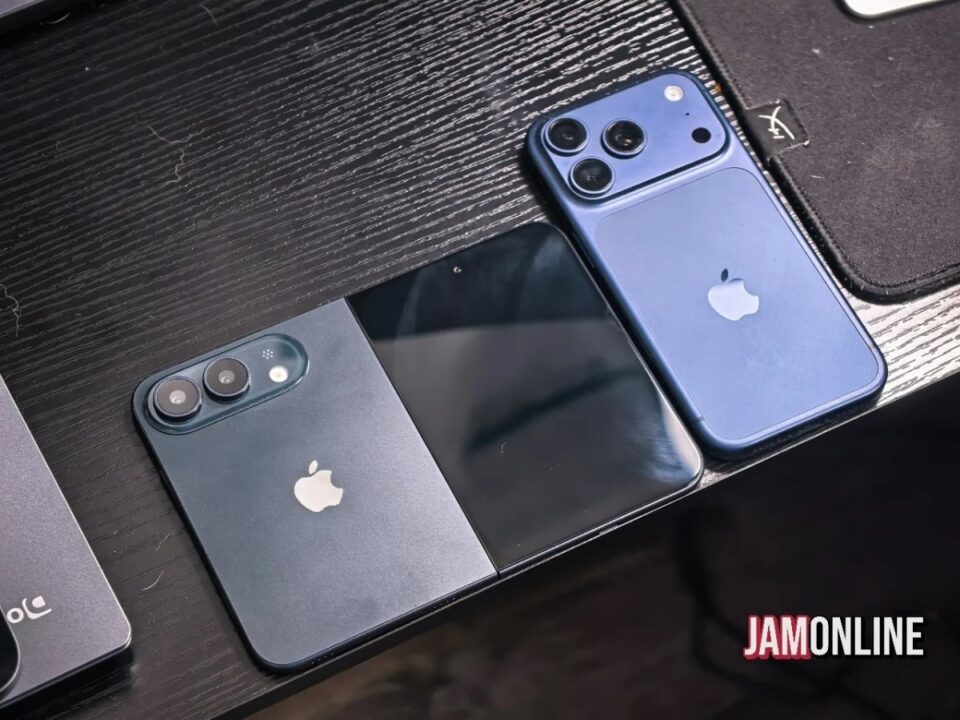 Three iPhones in blue and black finishes with triple-camera backs resting on a dark wooden desk, JAMONLINE watermark visible at bottom right.