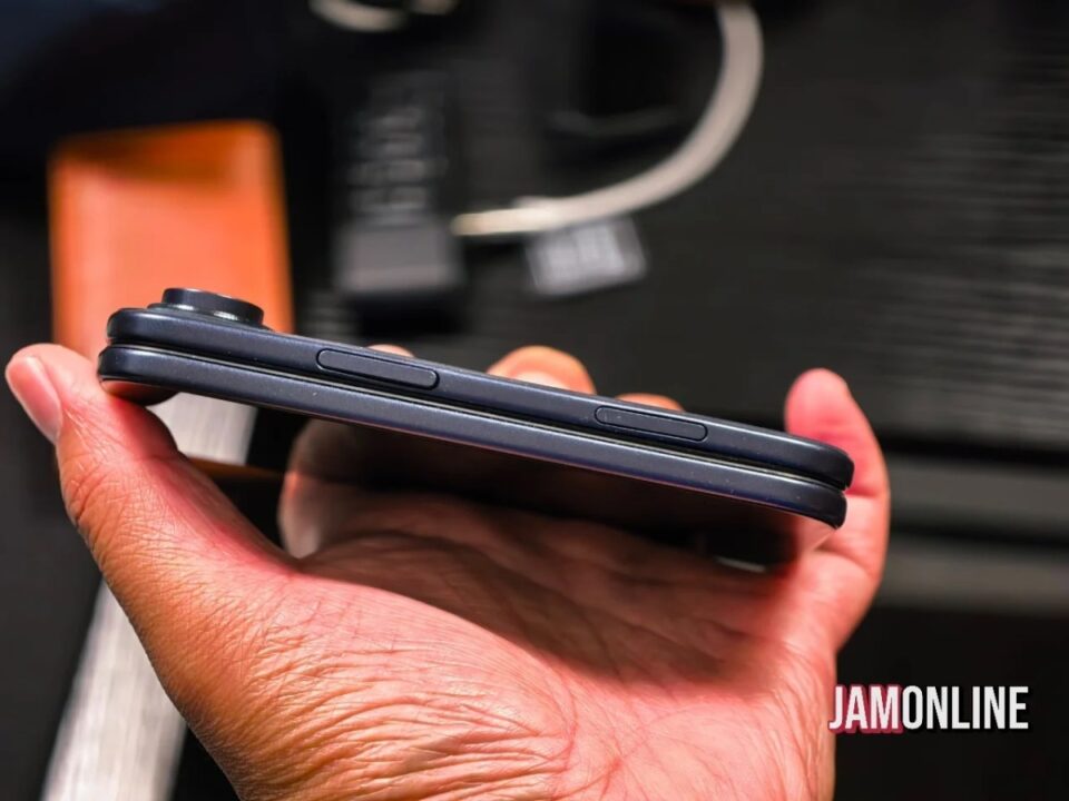 Close-up of a hand holding a dark smartphone from the side, showing two long side buttons on the edge.