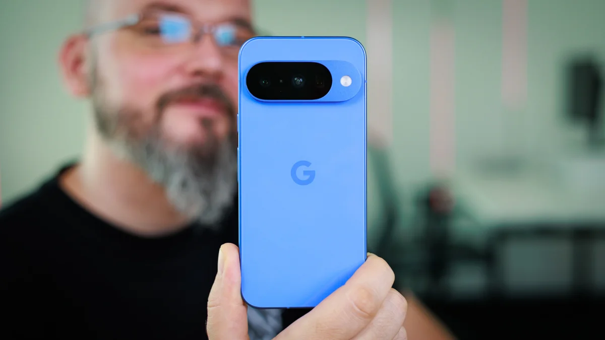 Blue Google Pixel smartphone held up to the camera, showing the rear camera bar and glossy blue finish.
