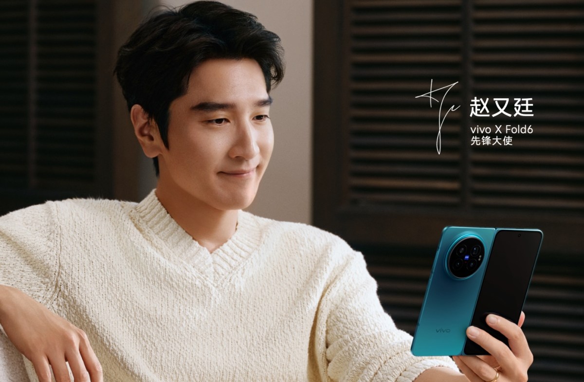 Man in a cream sweater smiles while holding a teal Vivo X Fold6 smartphone for a promo image, with branding text beside him.