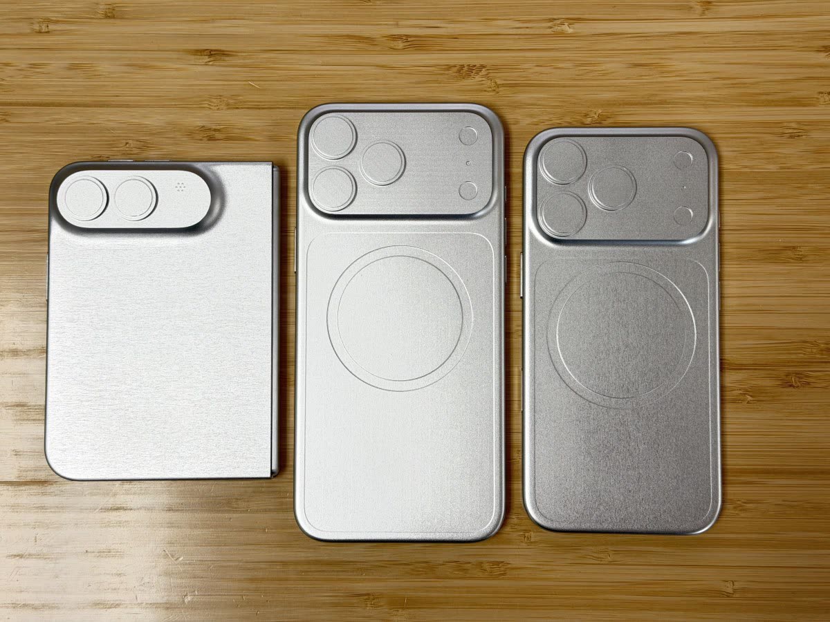 Top-down view of three silver metal smartphone cases with camera module cutouts on a wooden table, arranged side by side.