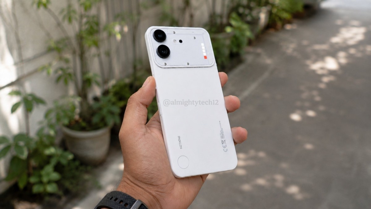 Person holding a white smartphone with a dual-camera rear setup outdoors along a sidewalk.