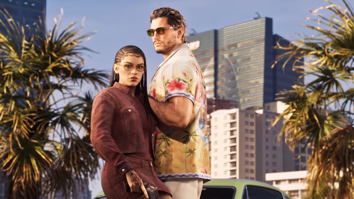 Two Stylish Adults Posing Close Together Outdoors in a Sunny City with Palm Trees and Tall Buildings Behind Them the Woman Wears a Maroon Jacket and Glasses the Man Wears a Floral Shirt and Sunglasses