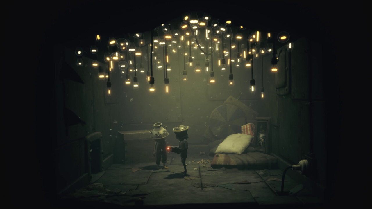 Two Small Humanoid Figures in a Dim Room Lit by a Chandelier of Hanging Bulbs One Offering a Red Glow to the Other Near a Bed and Scattered Debris