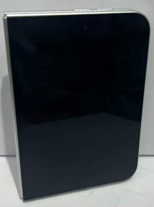 1000039871 Tall, black glossy rectangular device with rounded corners and silver trim, standing upright on a light surface.