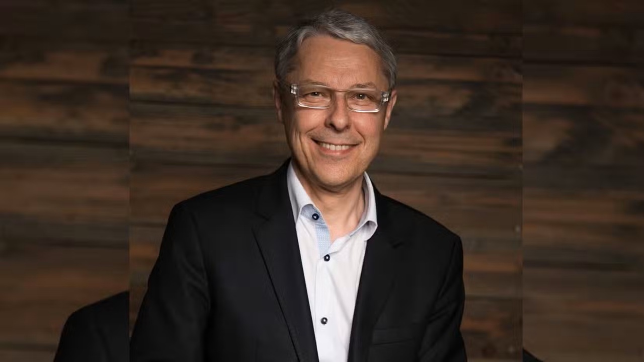 Smiling Man in a Dark Suit and Glasses Posing for a Professional Studio Portrait Against a Wooden Backdrop