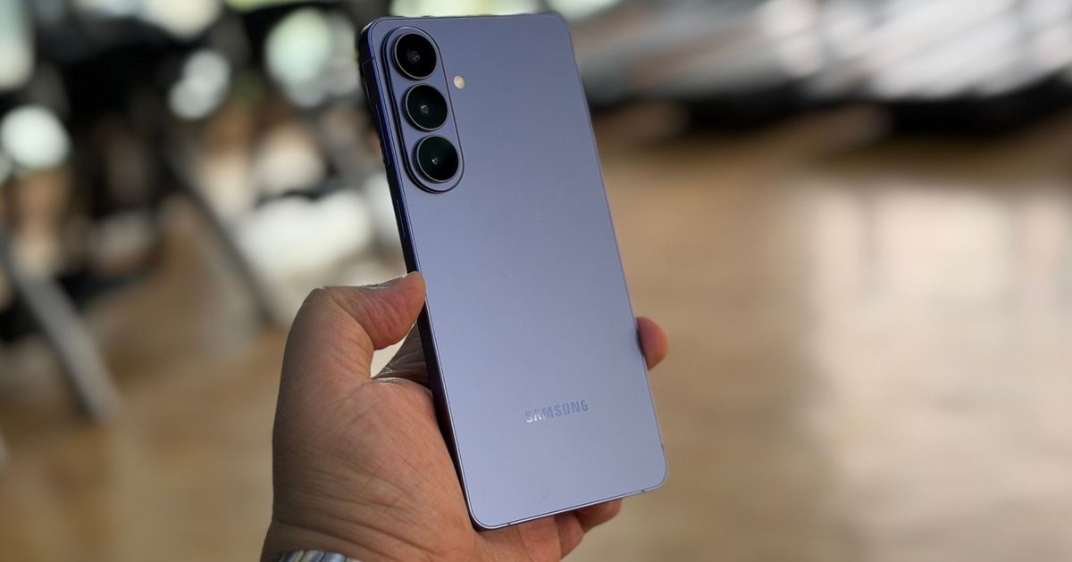 Purple Samsung Galaxy smartphone held in a person's left hand, showing its triple-camera rear setup.