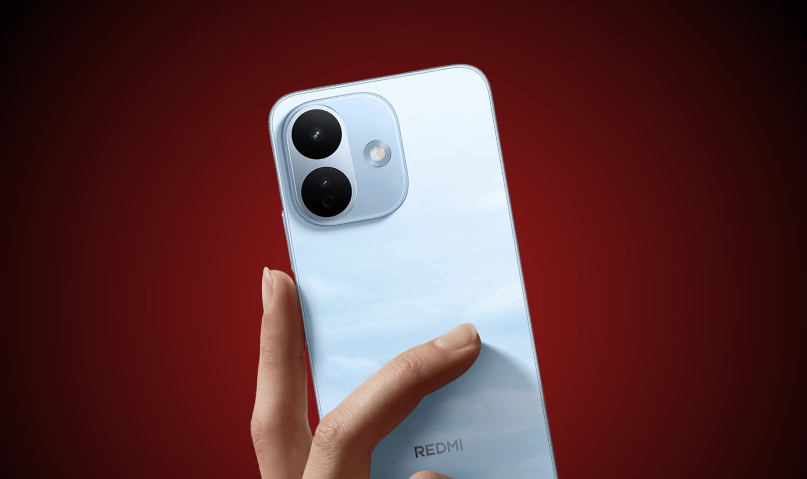 Rear view of a light-blue Redmi smartphone being held, featuring a prominent camera module and glossy finish against a red gradient background.