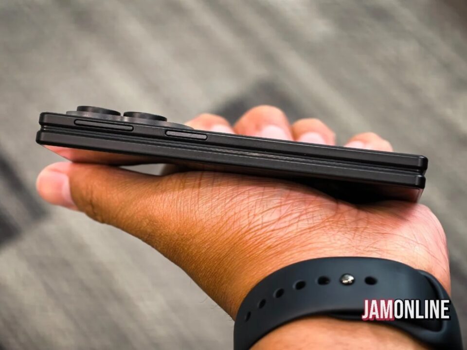 Close-up of a hand holding a black foldable smartphone from the side, showing the side buttons edgewise.