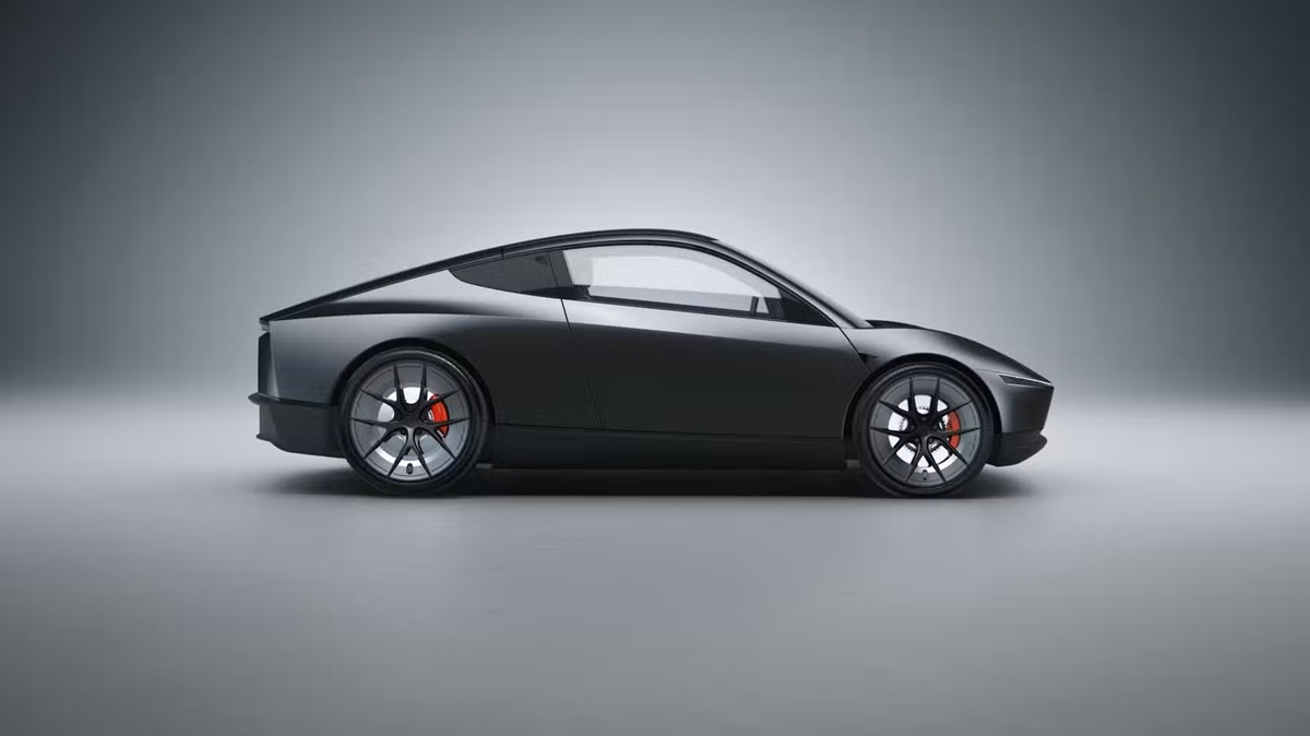Side view of a sleek dark sports car with large wheels and red brake calipers in a gray studio setting, low and aerodynamic profile.