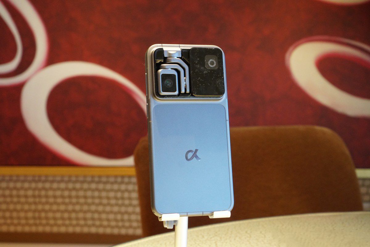Blue smartphone back with a prominent multi-lens camera module, displayed on a stand.