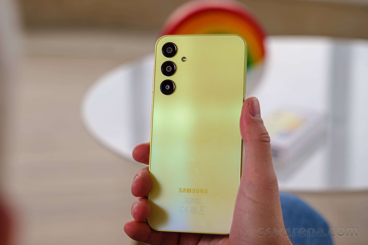Back of a yellow Samsung phone with three vertically aligned cameras held in a hand