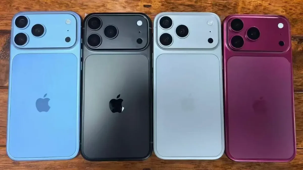 Four iPhones lined up on a wooden surface, showing rear cameras in blue, black, silver, and magenta colors.