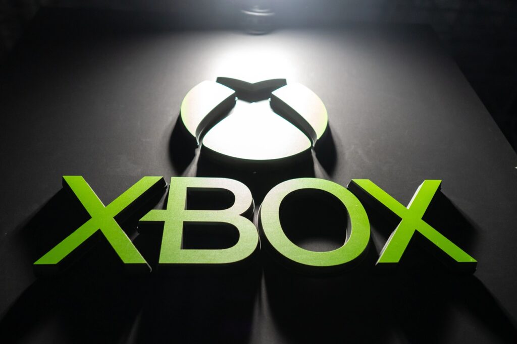 Xbox Logo Sign in Bright Green Lettering on a Dark Surface with a Circular Light Feature Above