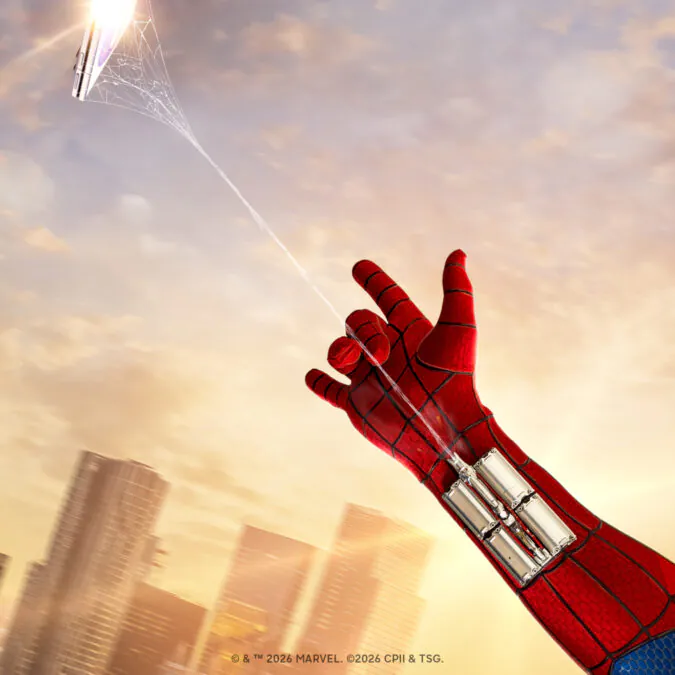 Spider-Man's red gloved arm reaches upward, shooting a web toward the sky above a city skyline.