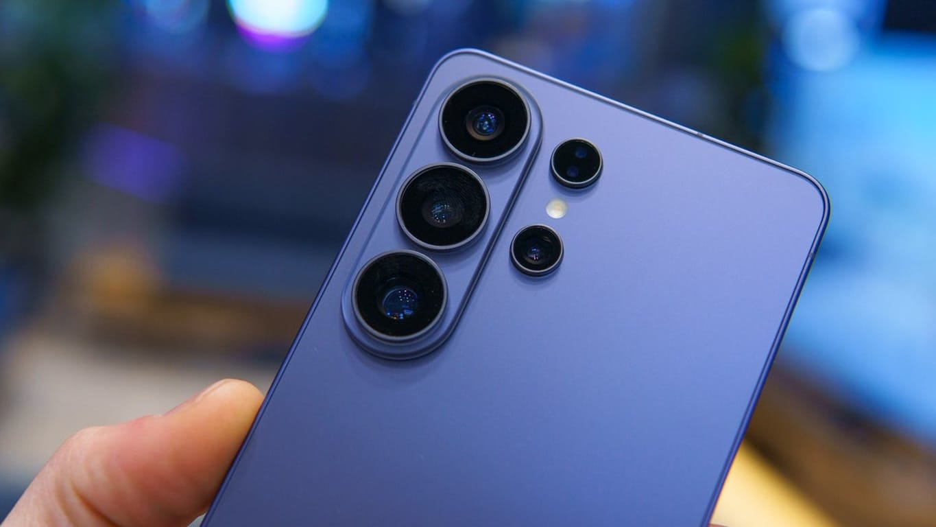 Blue smartphone back featuring a quad camera array with one large lens at the top-left and three smaller lenses arranged nearby, plus a small flash.