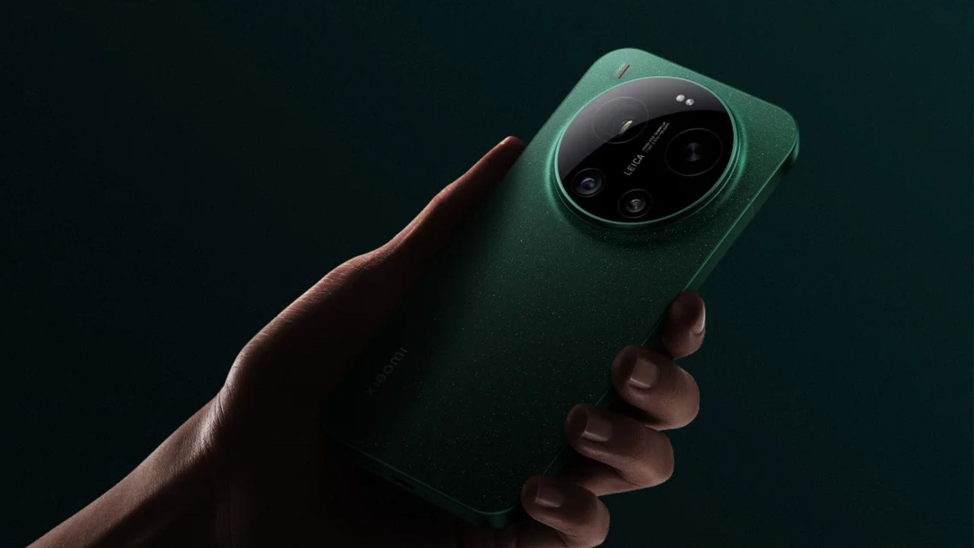 Hand holding a green smartphone with a large circular camera module on the back against a dark background, viewed from the side.