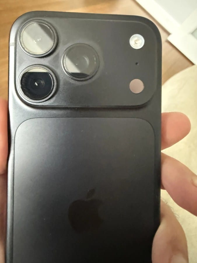 Back of a dark iPhone showing the triple-camera module and Apple logo on a matte finish.