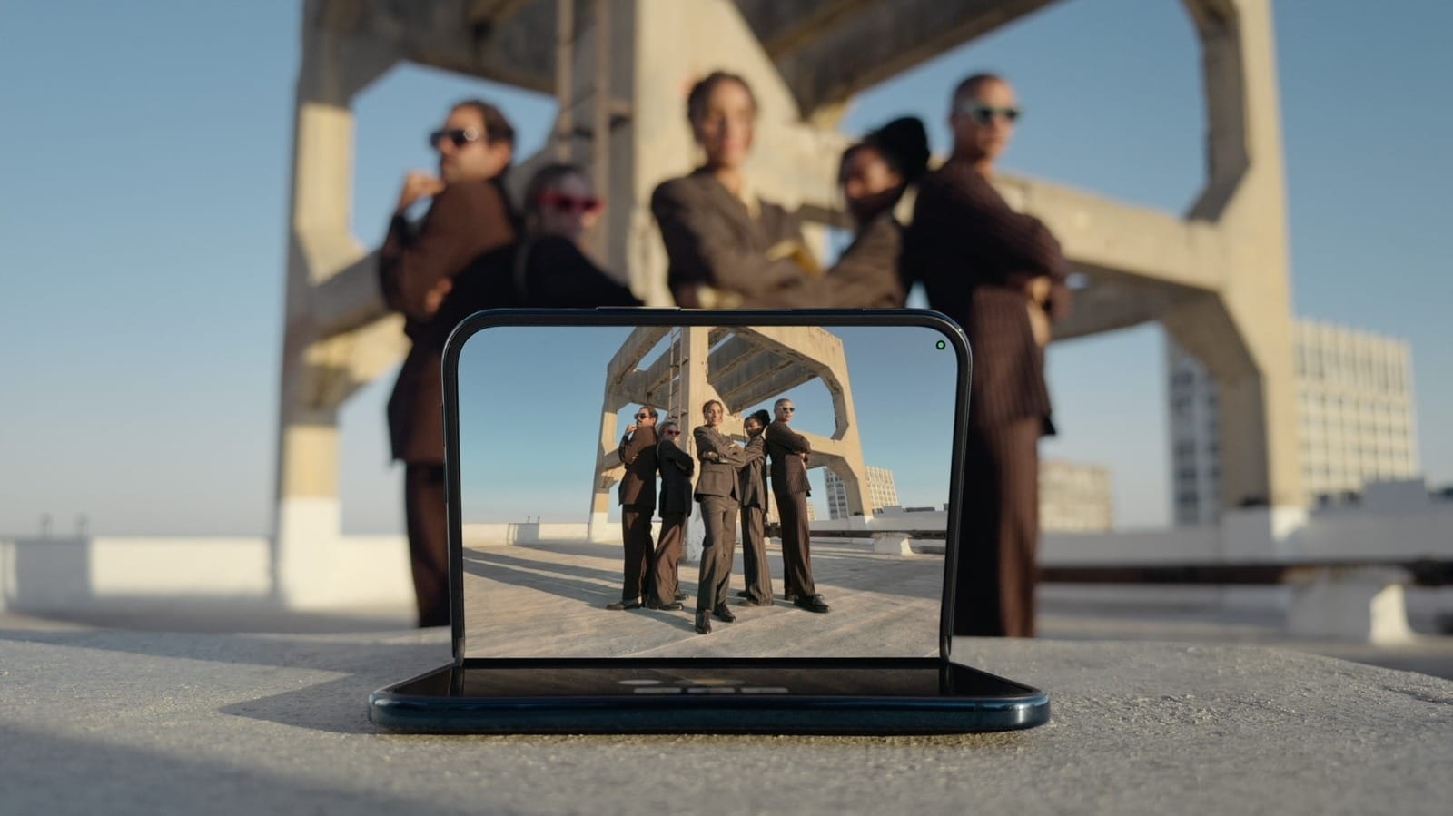 Group of professionals in business attire posing on a rooftop, shown on a smartphone screen facing the camera.